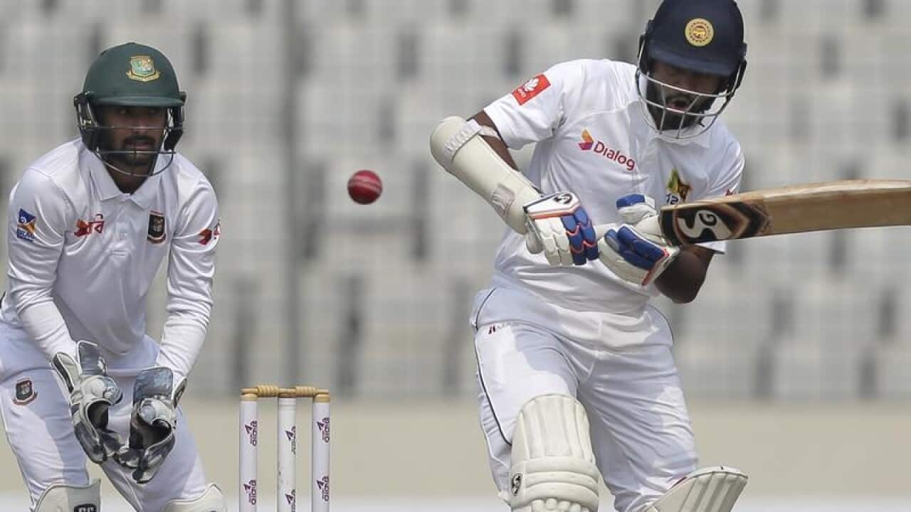 Sri Lanka's Dimuth Karunaratne (R) plays a shot