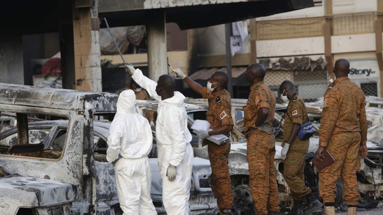 Forensic workers in protective clothing and Burkina Faso soldiers
