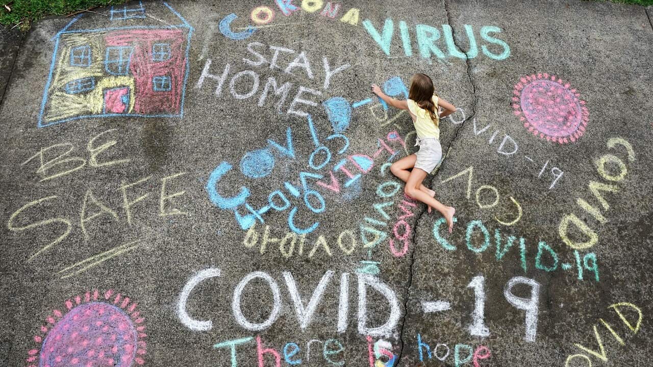 A girl writes with chalk on her home driveway on the Gold Coast