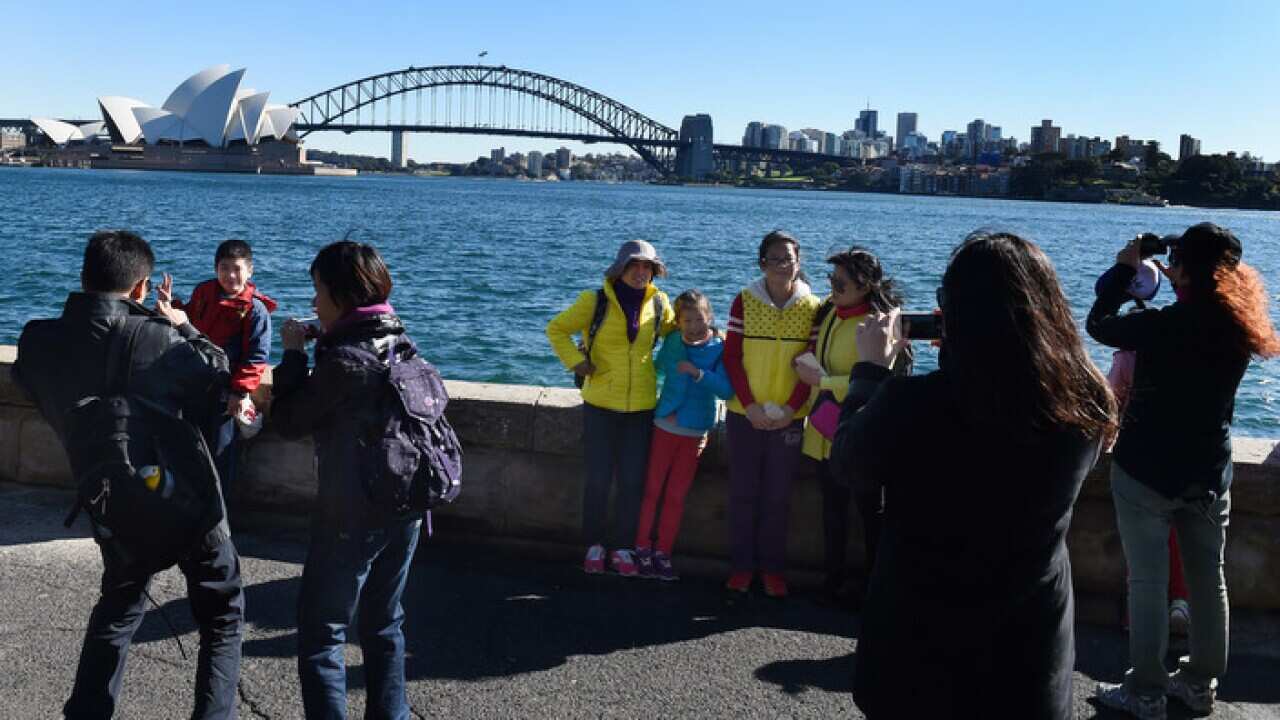 Chinese tourists take in the sites of the Sydney Harbour Bridge and the Sydney Opera House from Mrs Macquarie's Chair in Sydney, Tuesday, July 14, 2015. (AAP Image/Dean Lewins)