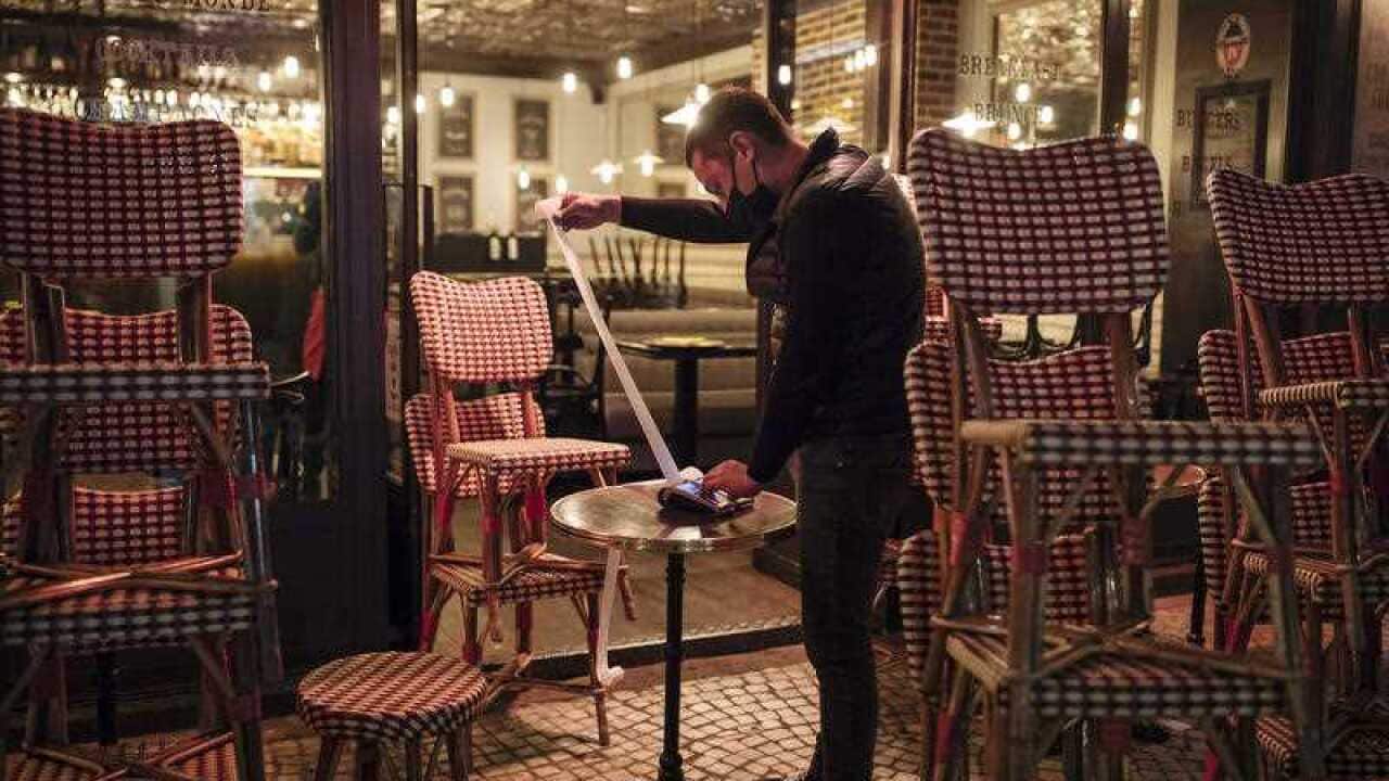 A waiter checks the final revenue as he closes a bar terrace in Paris on 17 October.