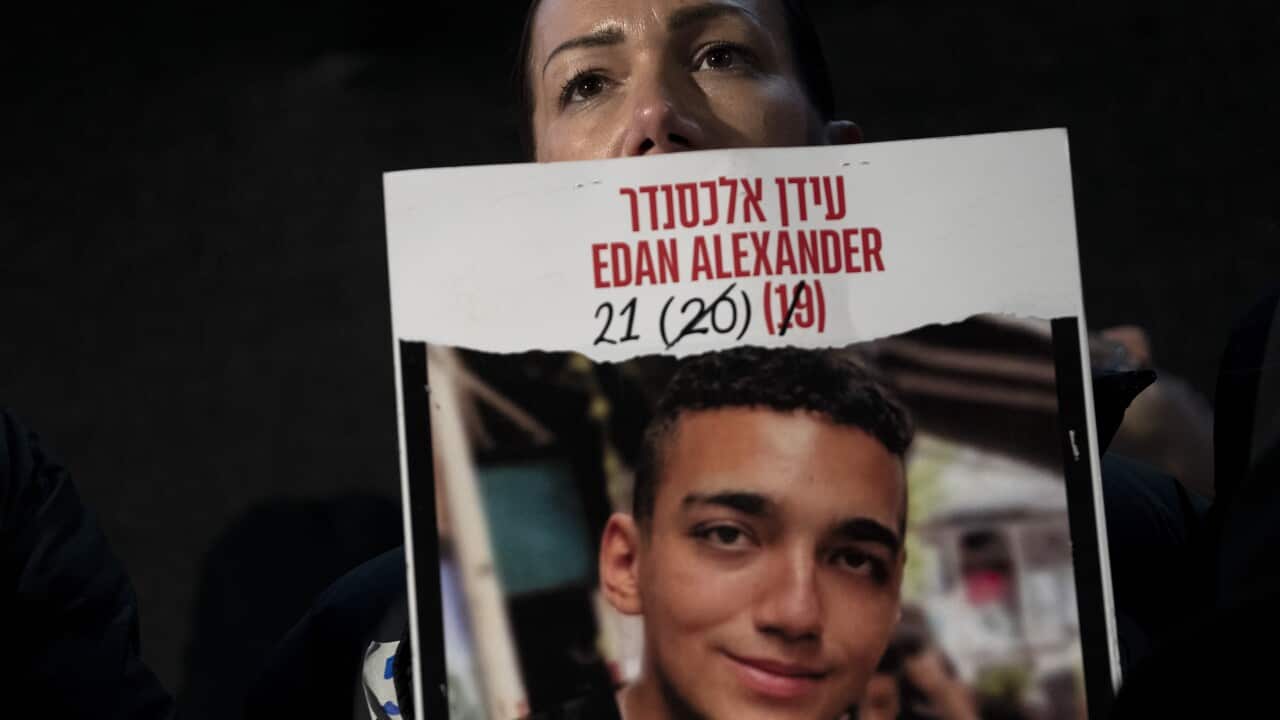 A woman holding a poster of a young man