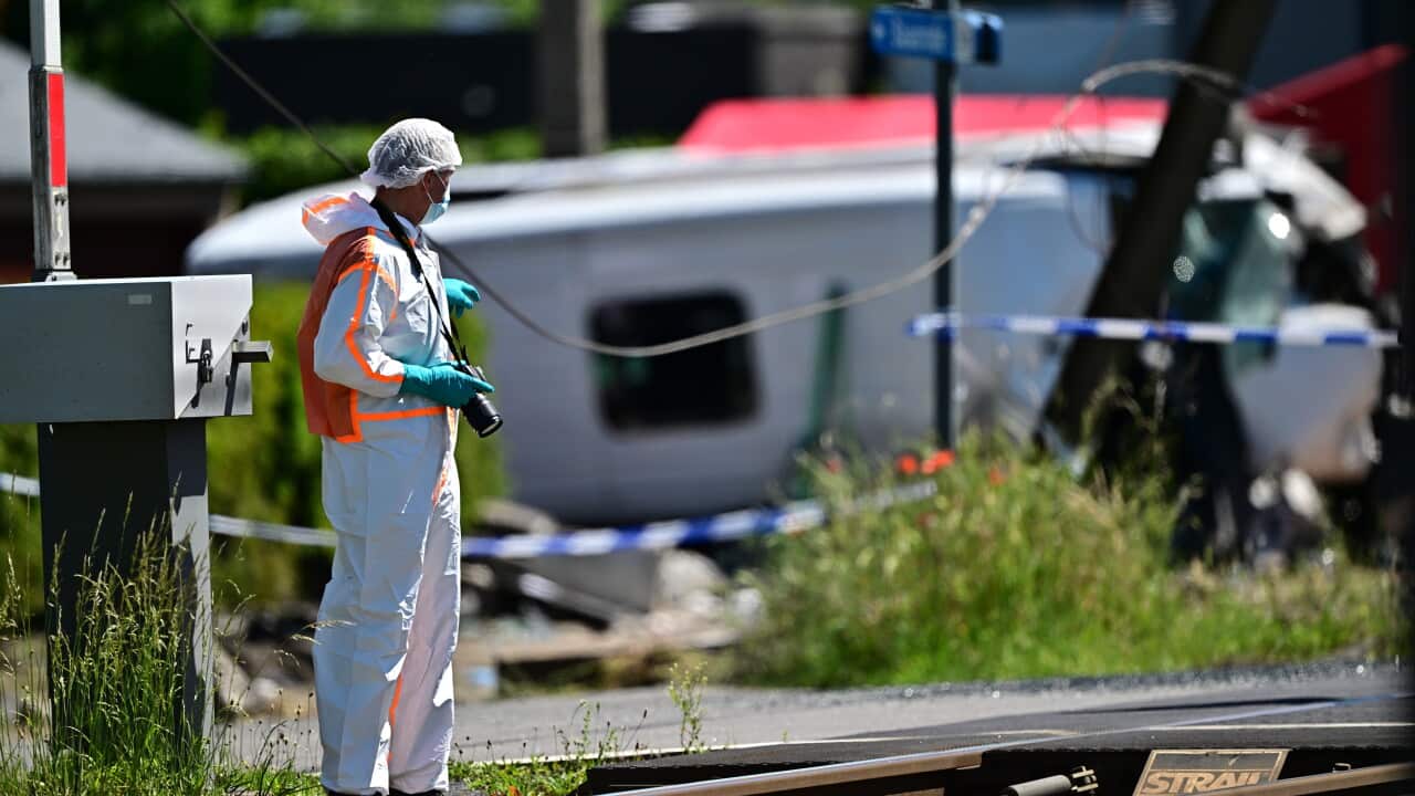 A person dressed in protective clothing stands next to a train line.