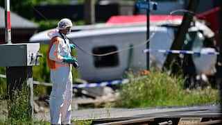 A person dressed in protective clothing stands next to a train line.