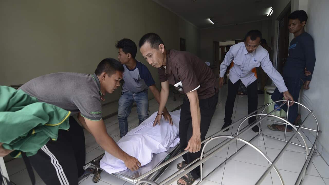 A family move the body of a victim who died from drinking poisonous bootleg liquor at a hospital in West Java, Indonesia.