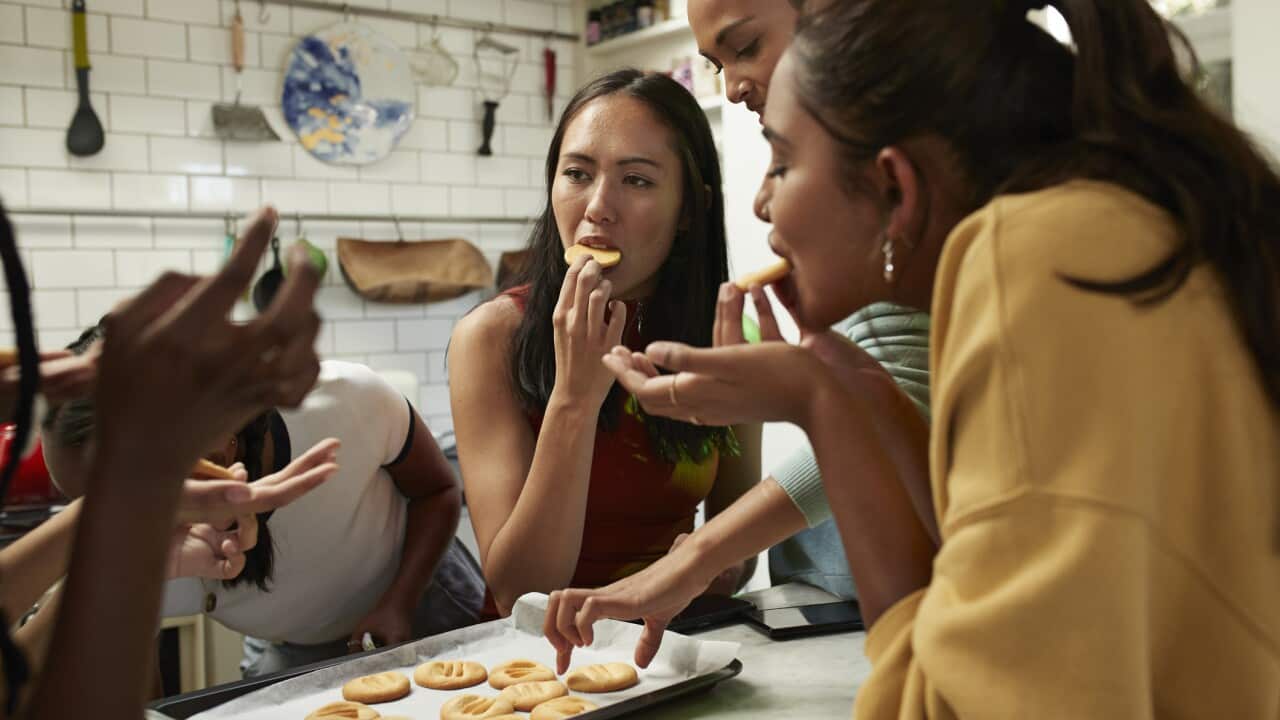 Friends eating fresh cookies in kitchen at home