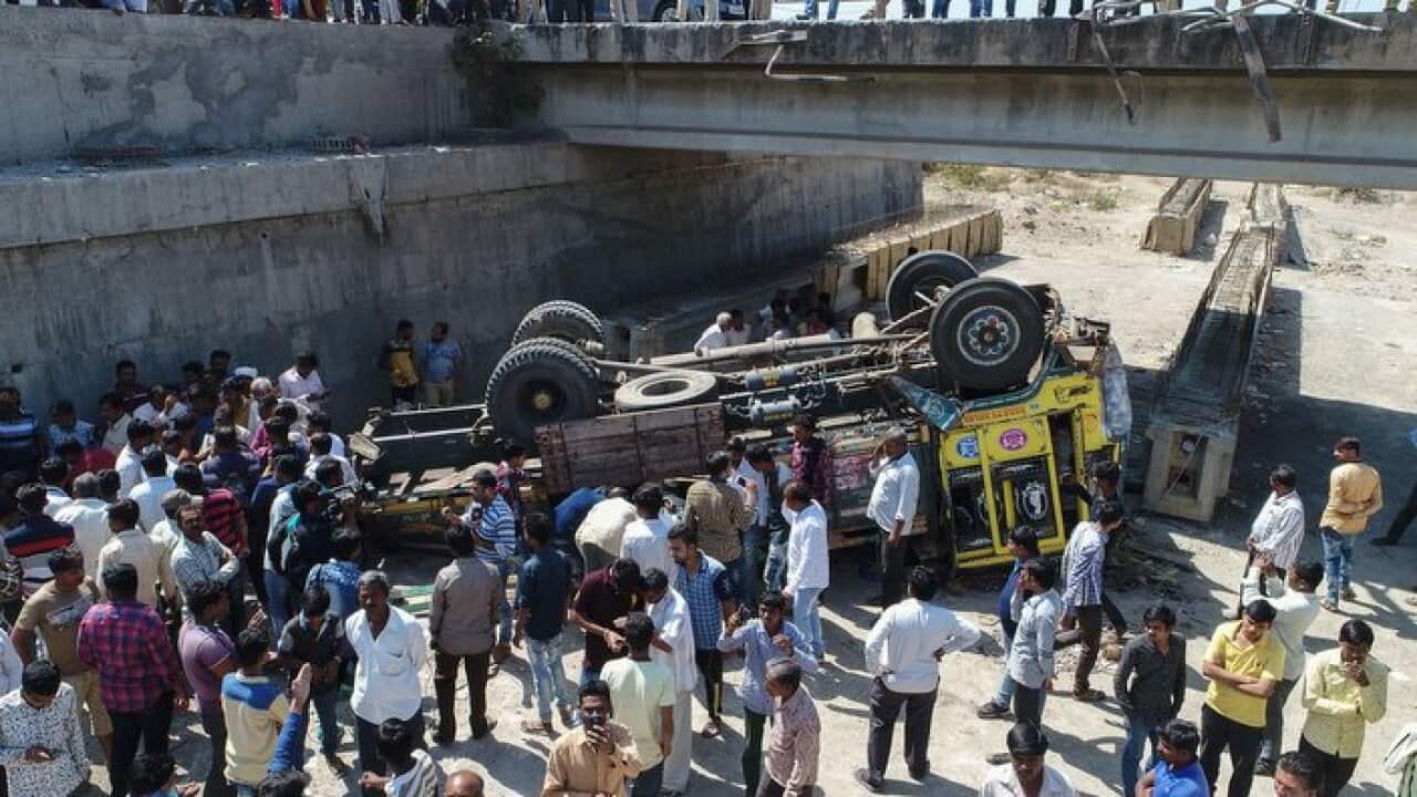 Onlookers gather around the debris of a truck that plunged off a bridge in Bhavnagar district, Gujarat state, killing at least 25 people on March 6, 2018.
