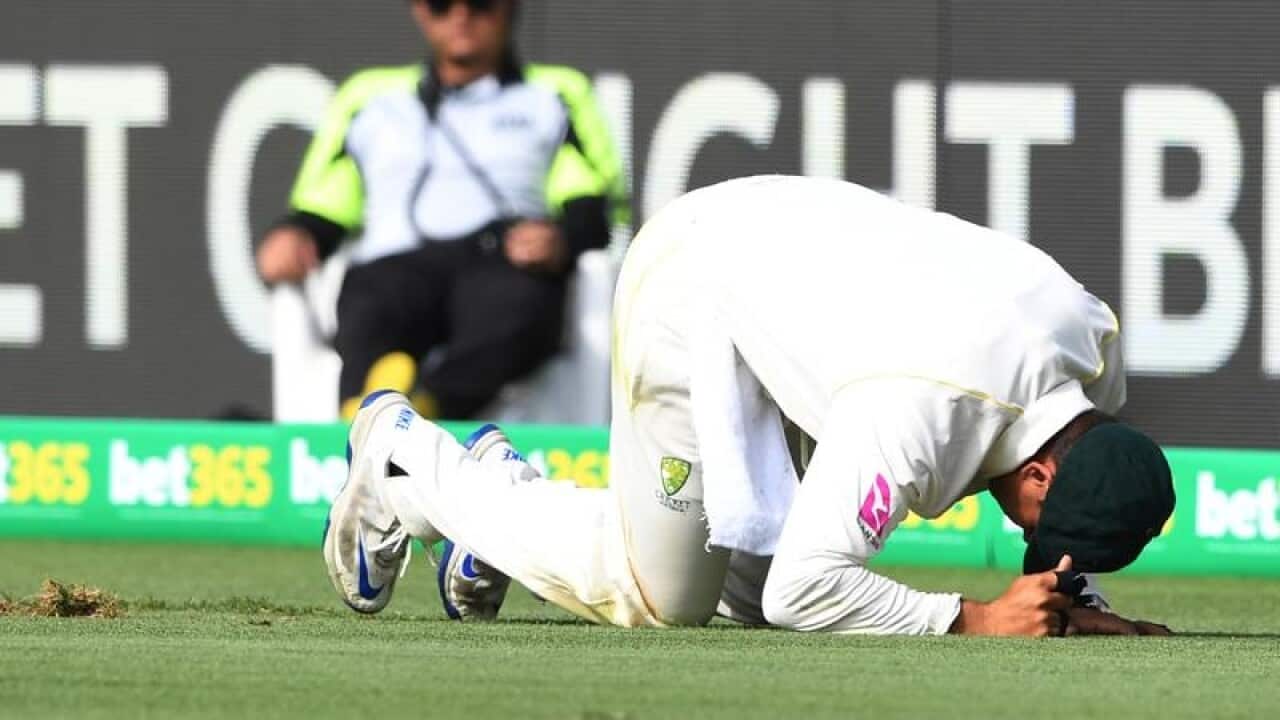 Australia's Usman Khawaja kneels on the pitch