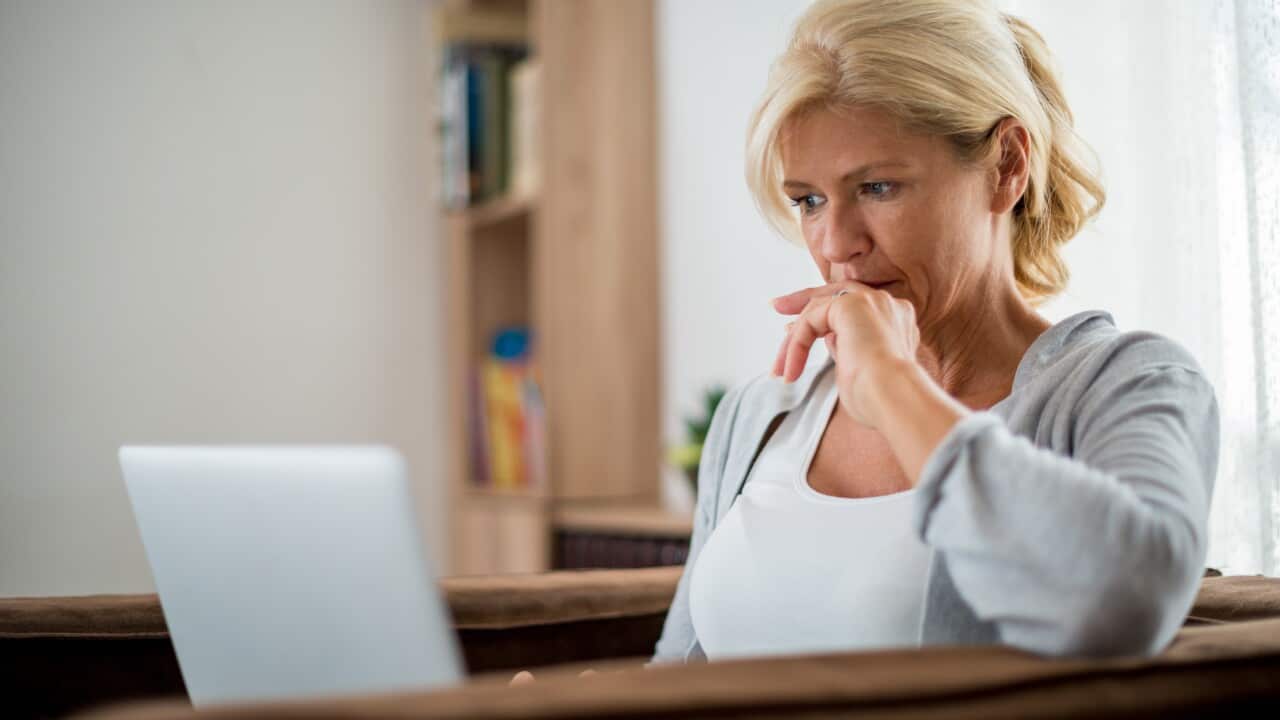 A woman sitting down using her laptop.