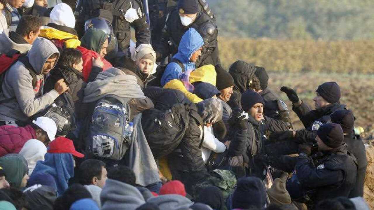 Migrants enter Croatia from Serbia as Croatian police officers stand guard the fence at a border between Serbia and Croatia, near the village of Babska, Croatia