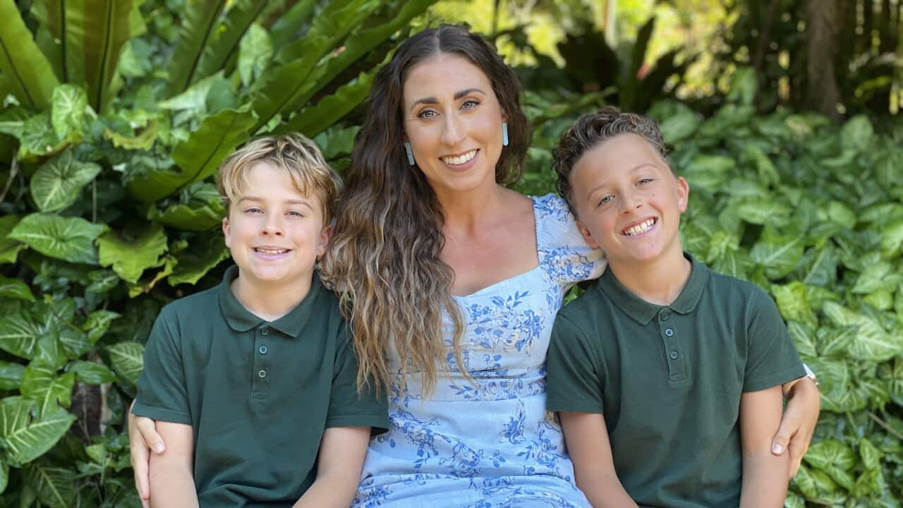 Clarissa Valentine sits with her arms around her two twin 12-year-old sons, who are both wearing green polo shirts.