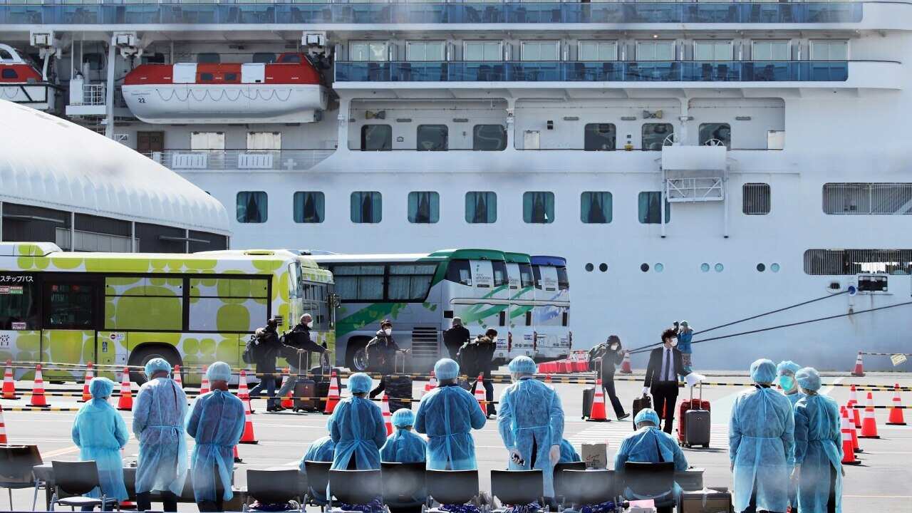 Workers in protective gear prepare to check passengers after they disembarked from the Diamond Princess cruise ship.