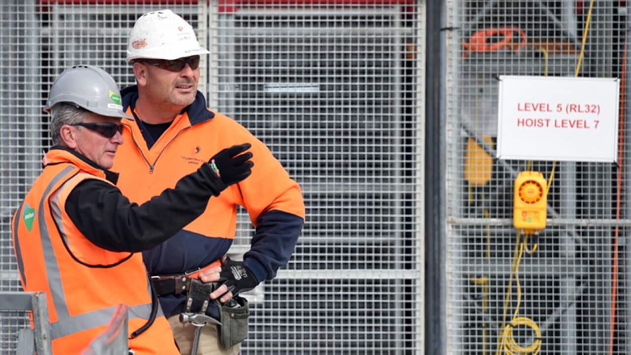 Construction workers wait for a lift at a work site