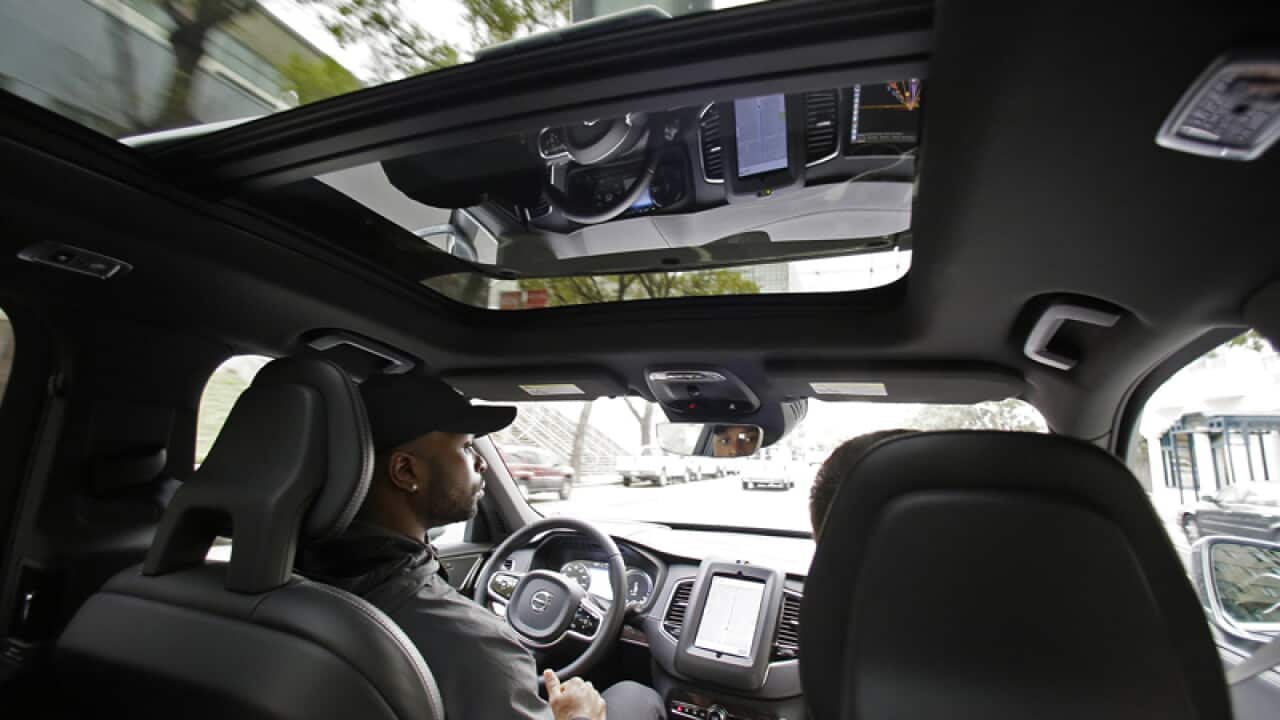 Devin Greene sits in the front seat of an Uber driverless car
