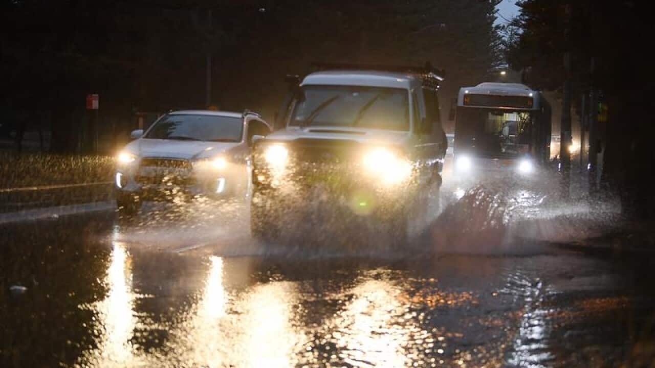 Morning commuter traffic negotiate the flooded Grand Parade.