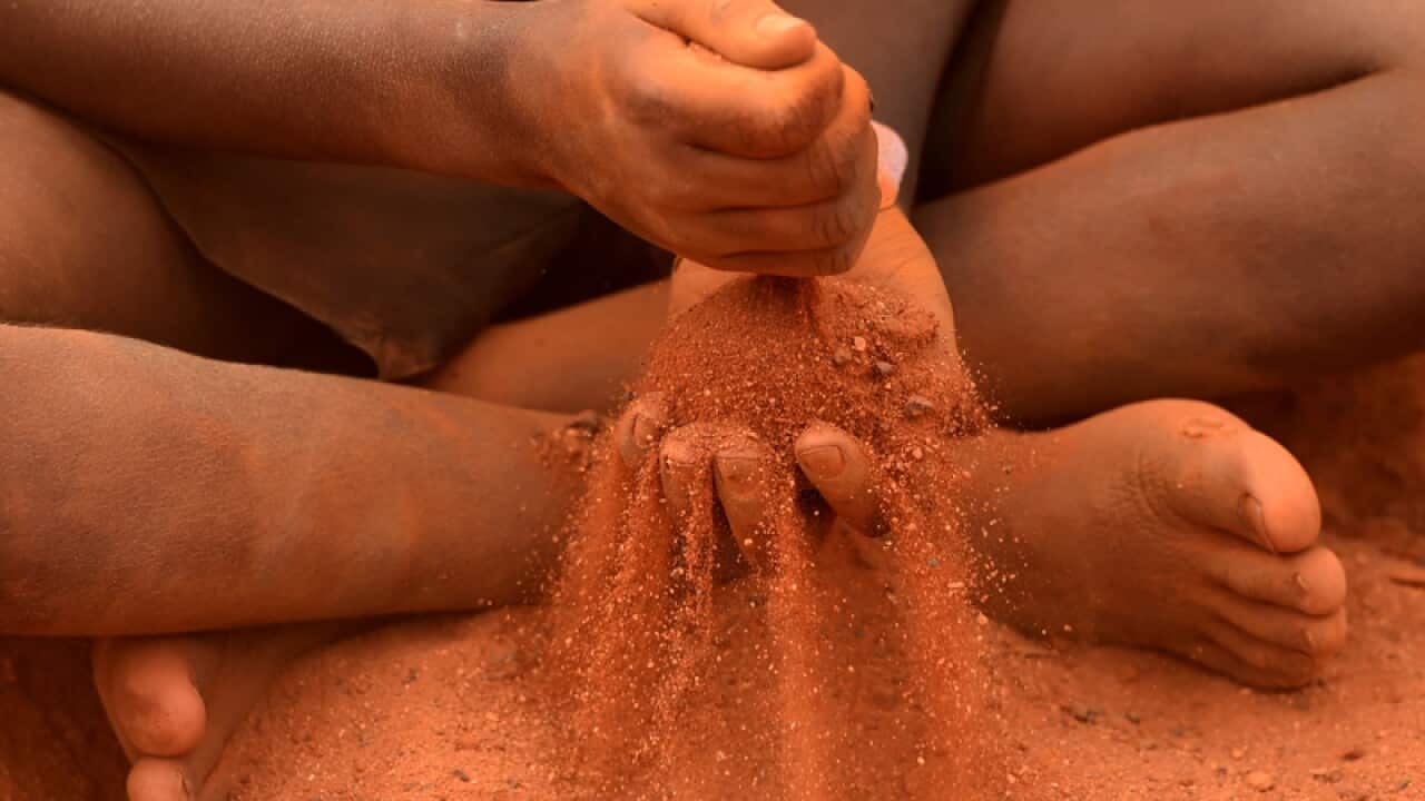 An indigenous child plays in red sand