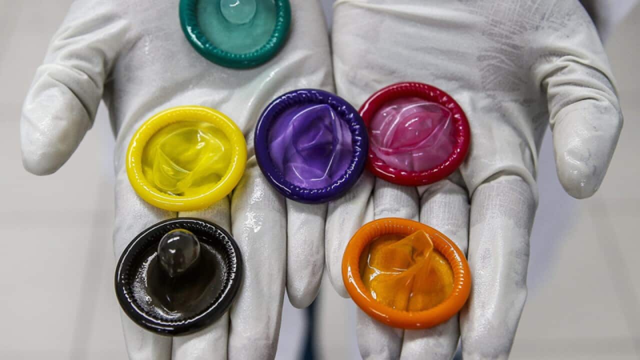 A worker holding a variety of coloured condoms