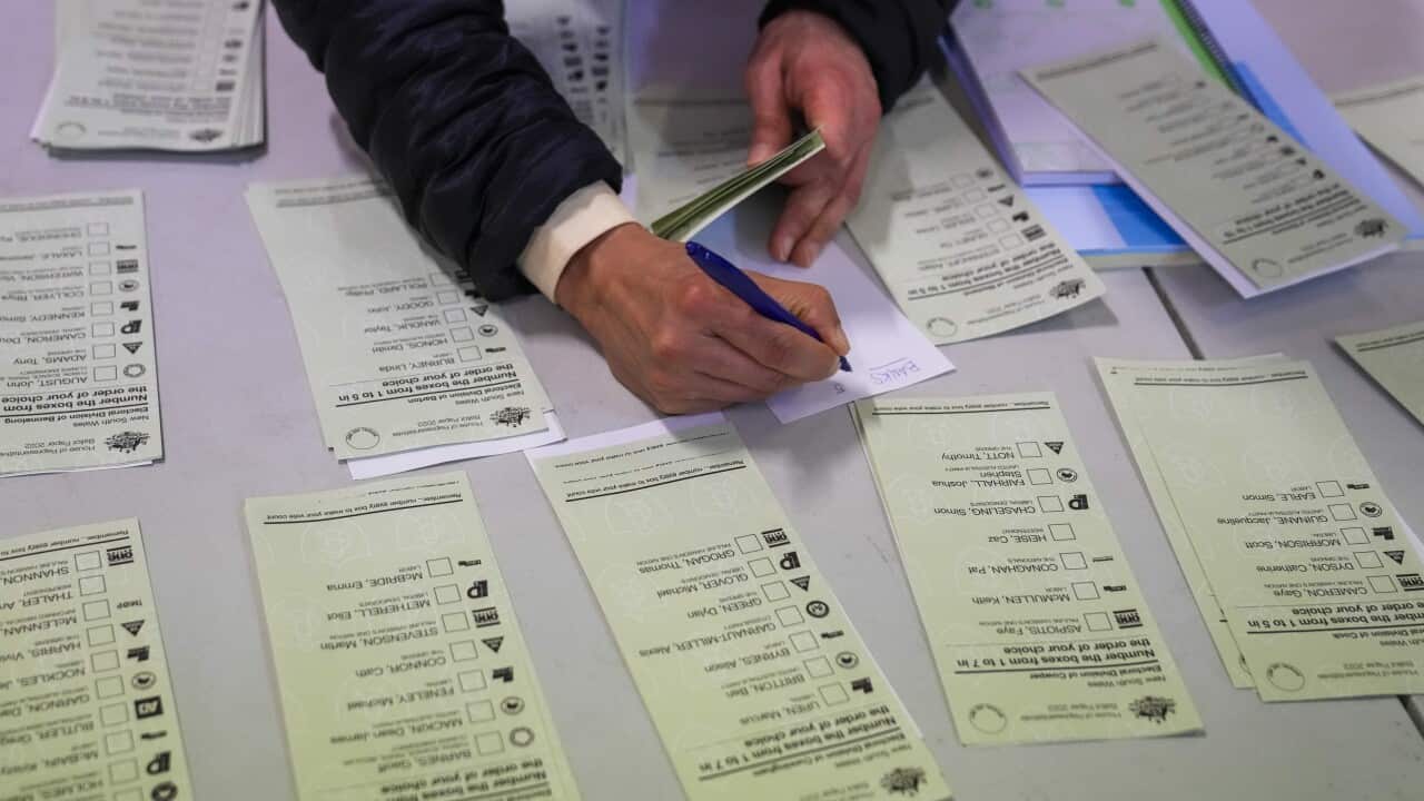 An electoral official prepares voting ballots at a polling booth.