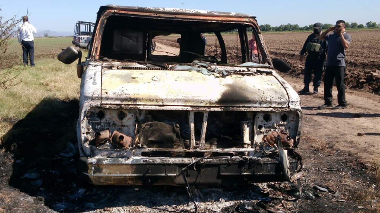 Mexican authorities inspect a burnt out van