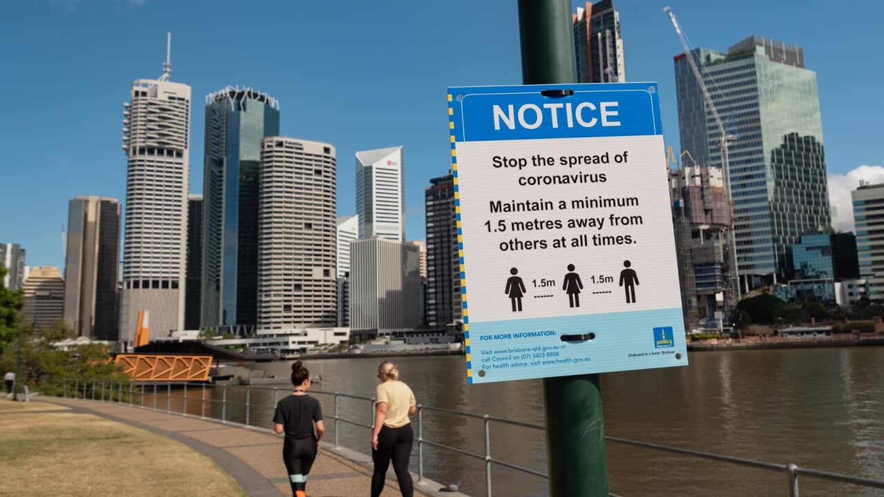 Two ladies walk past a sign warning the public about social distancing amid Covid-19 Coronavirus pandemic..
