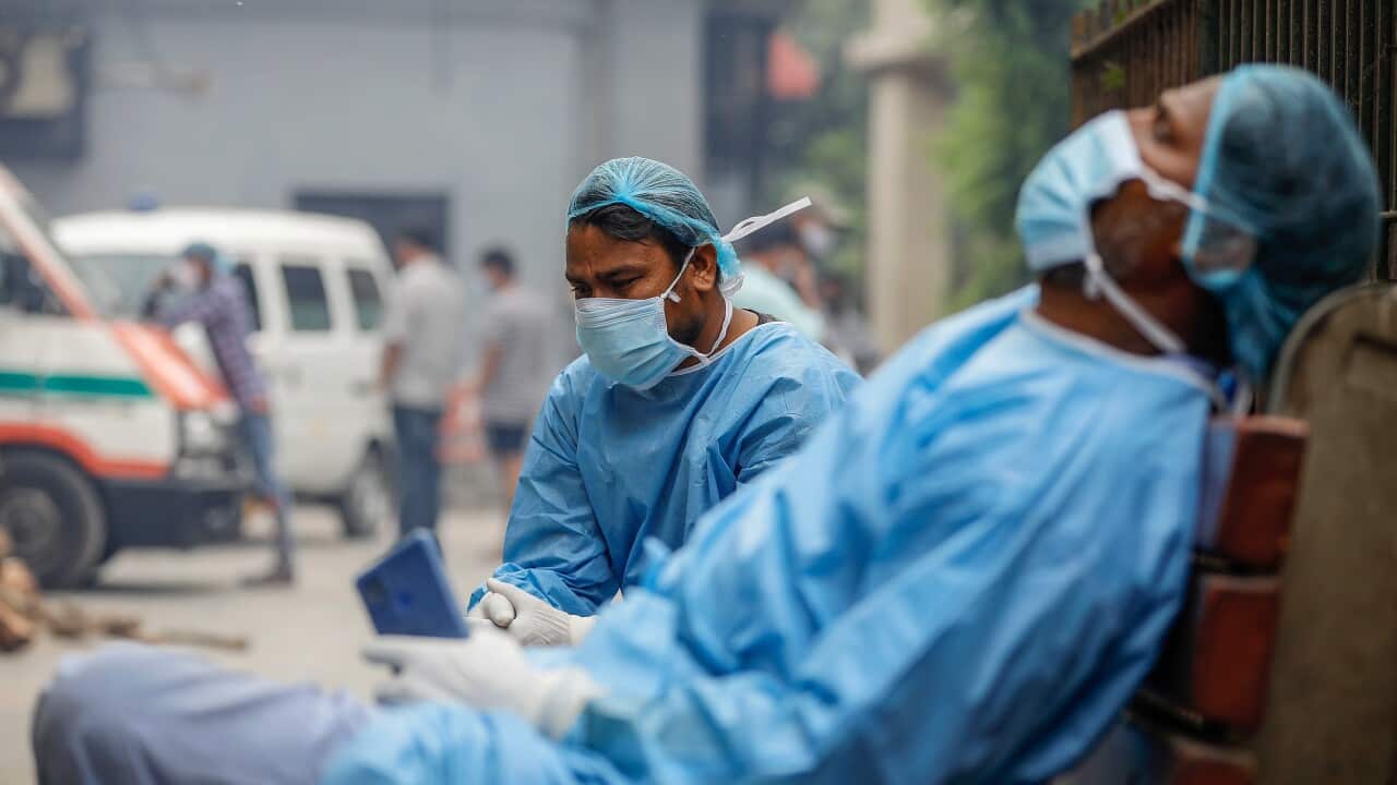 Cemetery workers helping cremate the bodies of COVID-19 victims take a break at a crematorium in New Delhi.