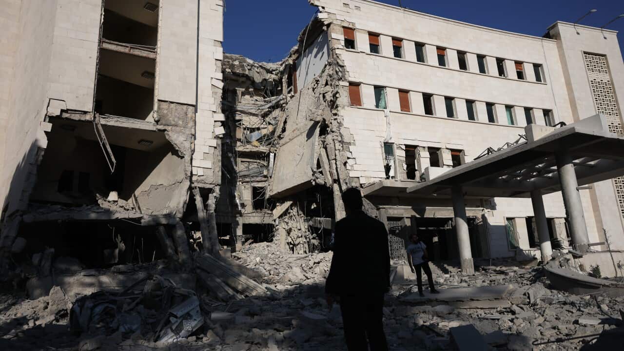 A person standing amid the rubble of a badly damaged building.