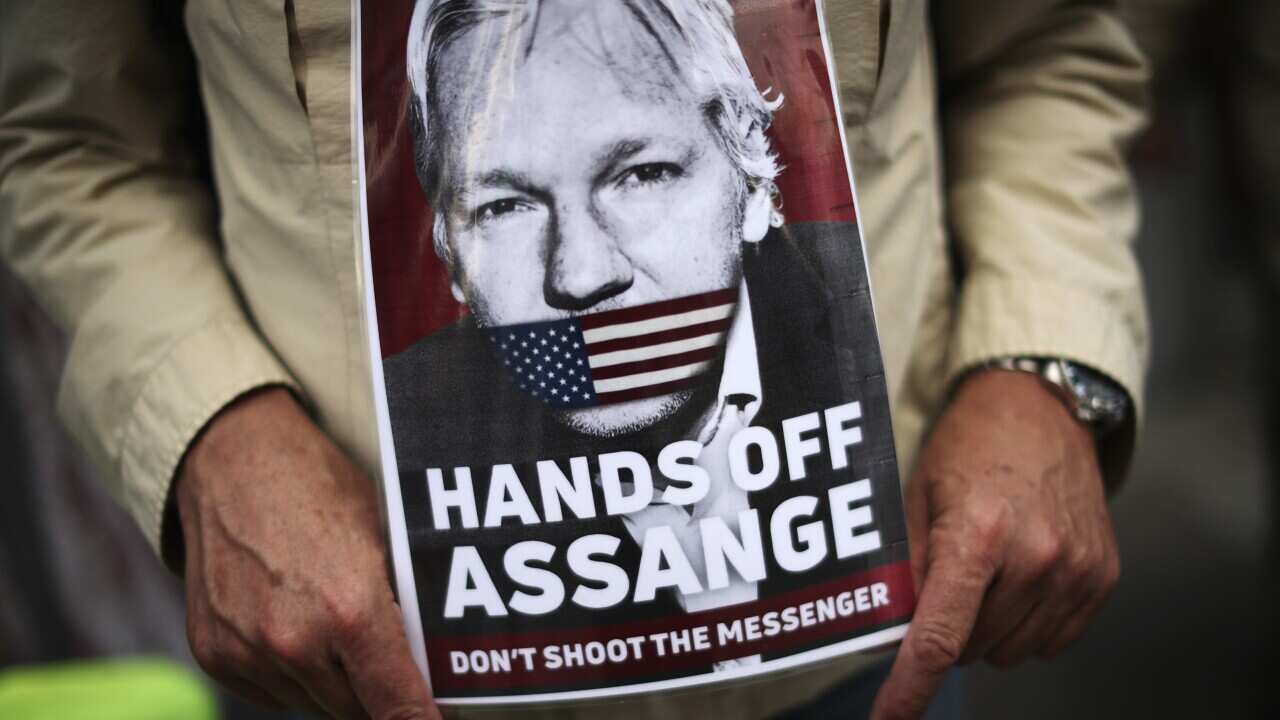 A man holds a photograph of WikiLeaks founder Julian Assange.