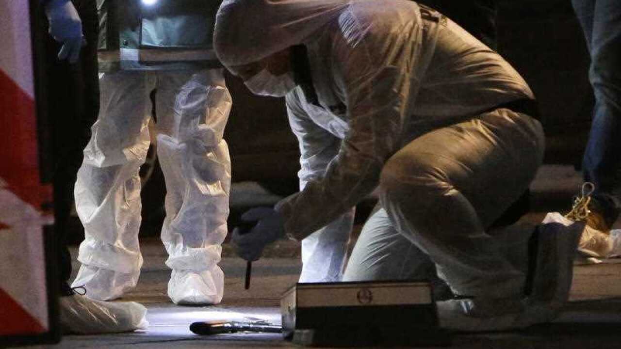 An investigating police officer looks at a gun, after the attack.