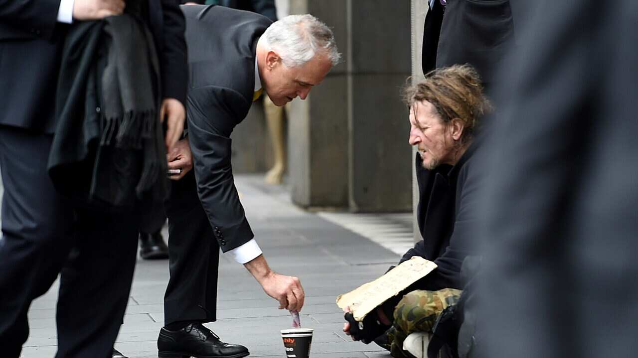Prime Minister Malcolm Turnbull gives a homeless man five dollars before giving his first major economic address since the Federal election to a CEDA audience in Melbourne, Wednesday, Aug. 17, 2016. (AAP Image/Tracey Nearmy) NO ARCHIVING