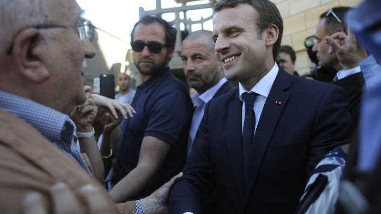 France's President Emmanuel Macron shakes hand with people