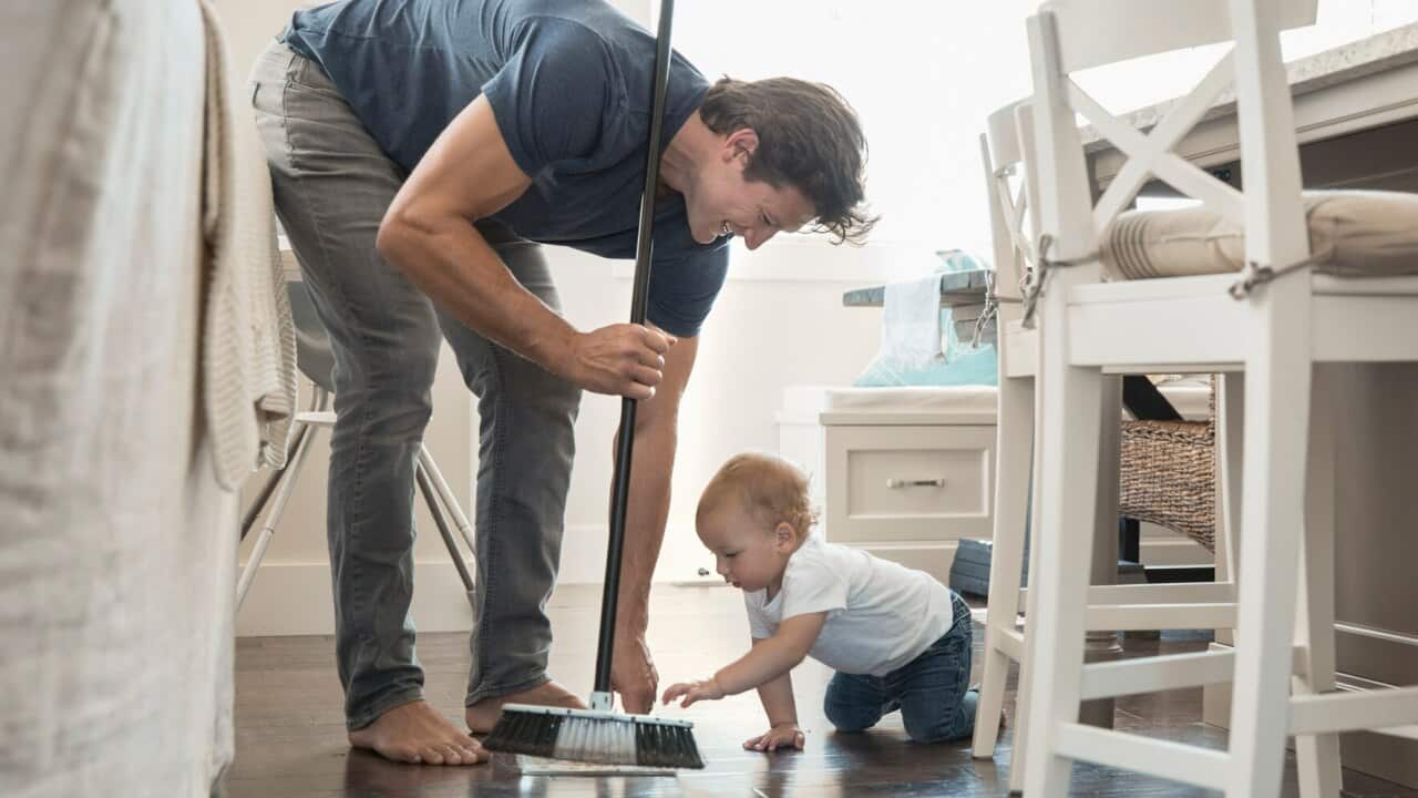 Baby son watching father sweeping floor