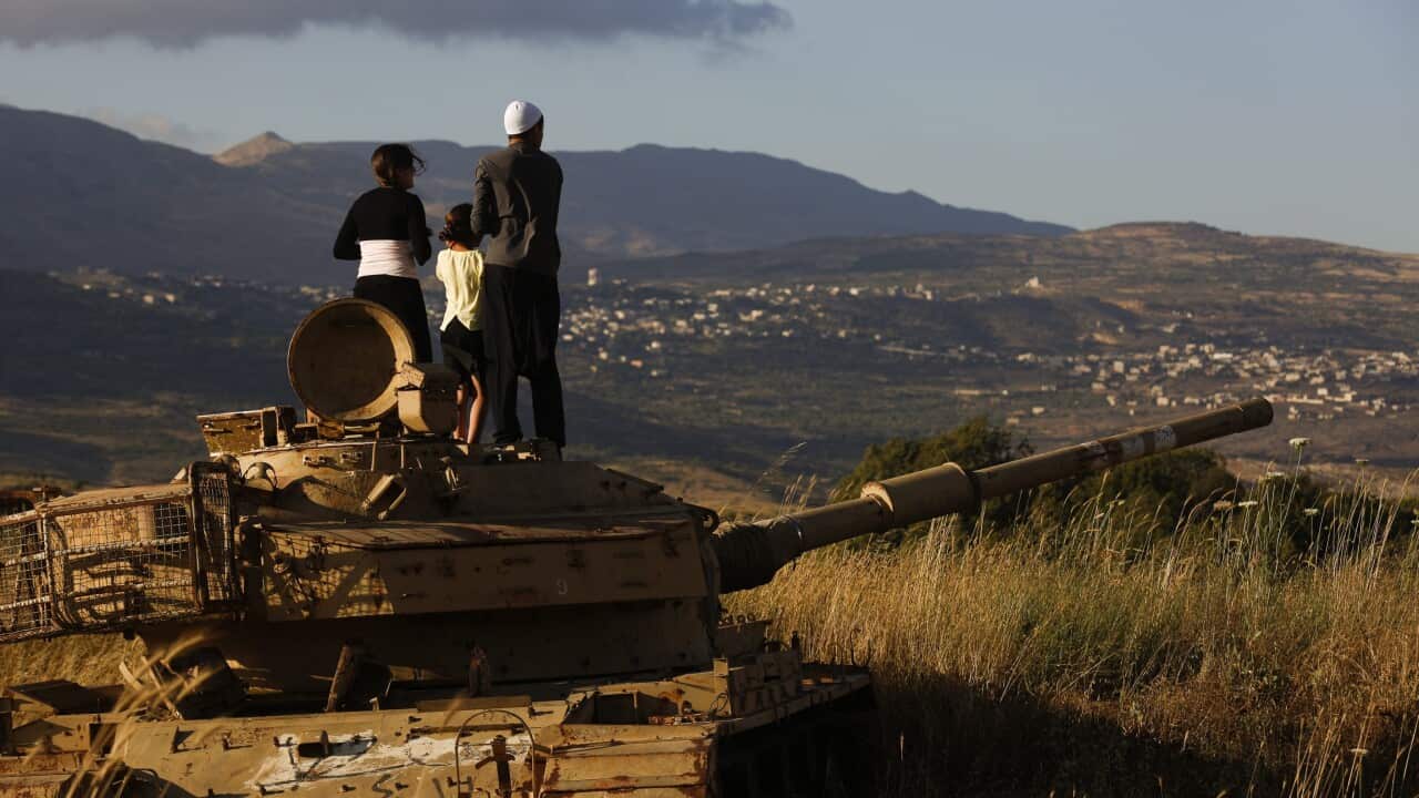 Young Druze cleric from the Golan Heights stand on top of an old Israeli tank to watch the fighting near the Druze village of Hadar (background) on the Syrian side of the border with Israel, 20 June 2015, during a fight with Syrian Nusra Front. (EPA)