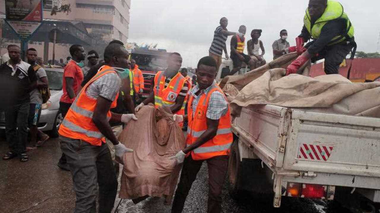 Rescue workers carry the remains, of a person onto the back of a truck after being killed in a gas station explosion in Accra, Ghana, Thursday, June 4, 2015. (AAP)