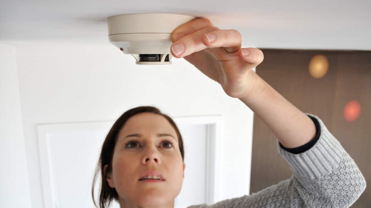 Woman checking smoke detector