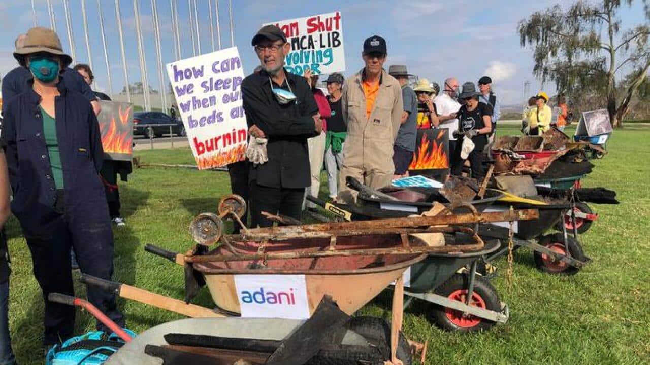 Bushfire survivors carry remnants of their properties in wheelbarrows outside Parliament House.