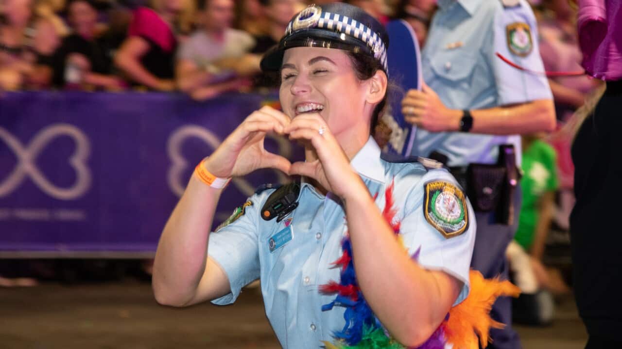 A woman in a police uniform holds her hands in the shape of a love heart.