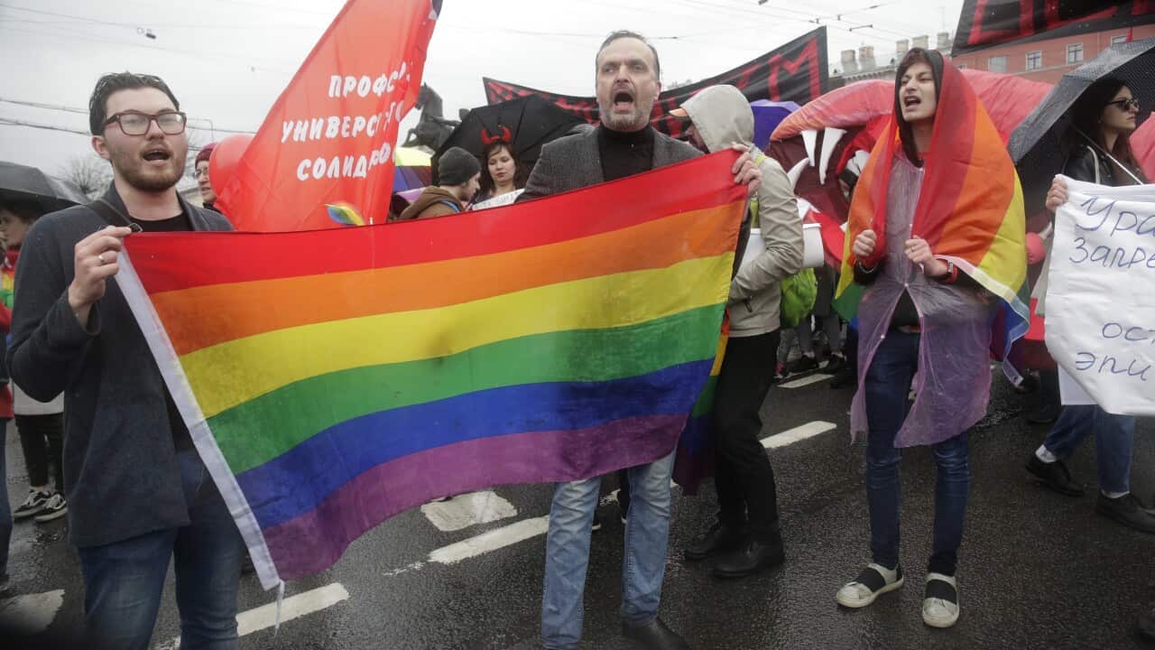 Two people holding a rainbow flag