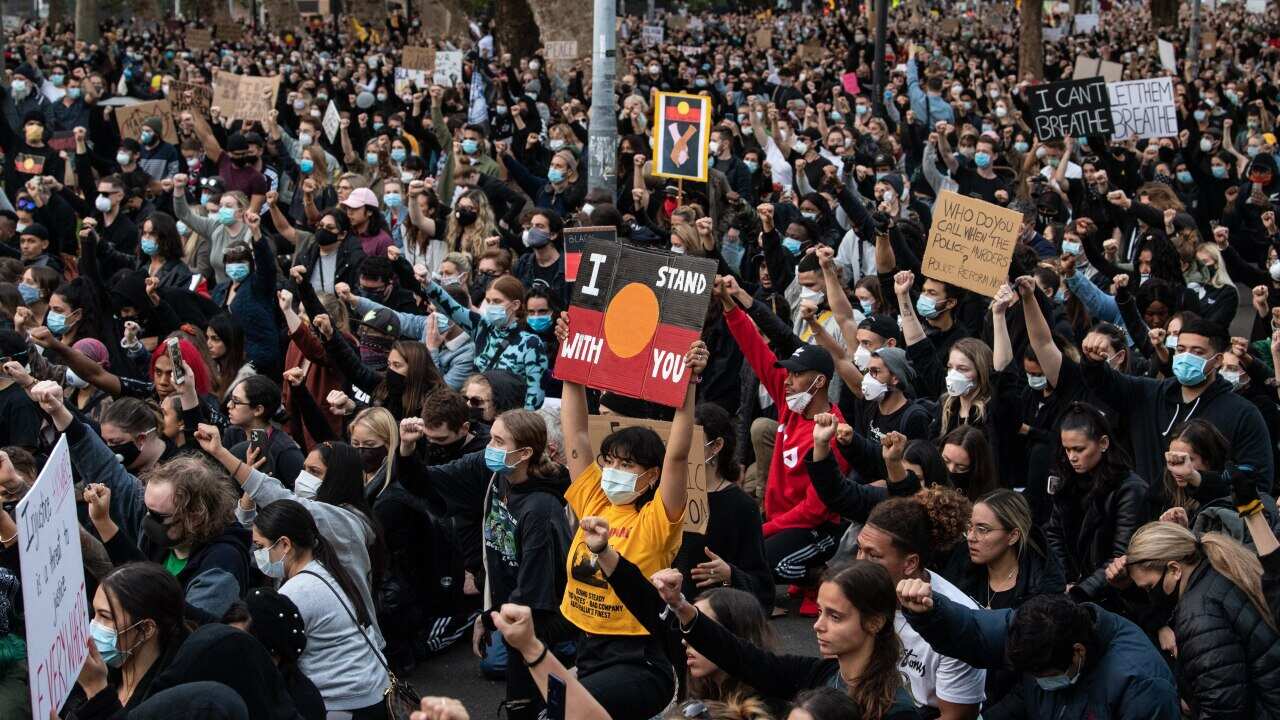 Thousands of protesters kneel and salute at a Black Lives Matter rally in Sydney.