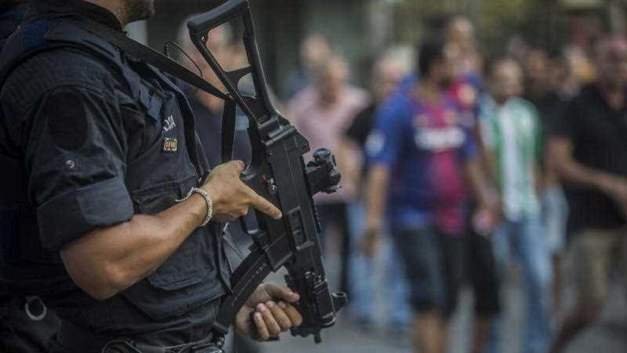 An armed police officer watches as fans walk towards the stadium before a La Liga soccer match between Barcelona and Betis at the Camp Nou stadium in Barcelona