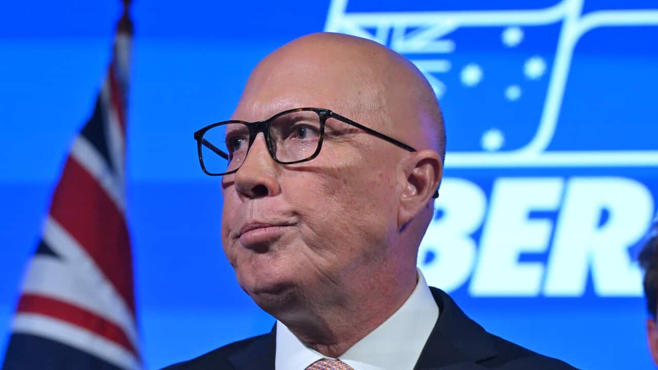 Peter Dutton purses his lips in front of an illuminated blue Liberal party backdrop.