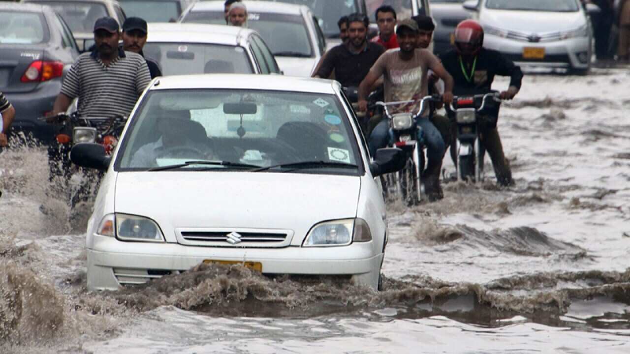 People make their way through a flooded street in Karachi
