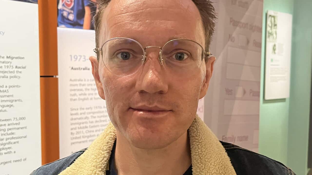 A man wearing glasses and a denim jacket, looking ahead at the camera for a portrait photograph.
