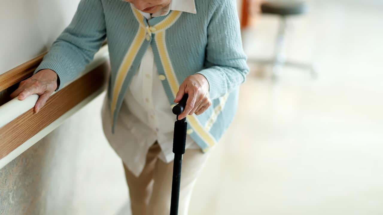 Senior woman walking with walking cane in hospital corridor. Photo by The Image Bank RF