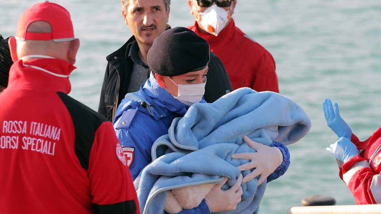 A Red Cross officer carries a baby wrapped in a blanket after surviving migrants disembarked at the Sicilian Porto Empedocle harbor, Italy, (AP Photo/Calogero Montanalampo)