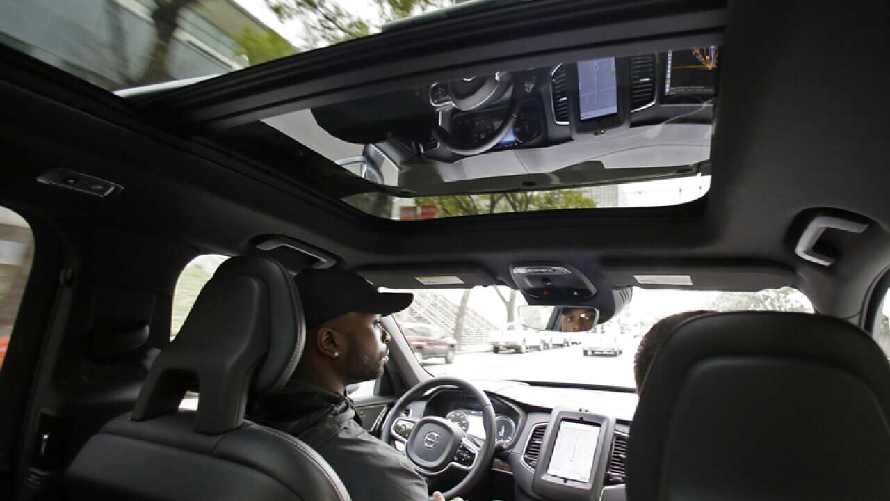Devin Greene sits in the front seat of an Uber driverless car
