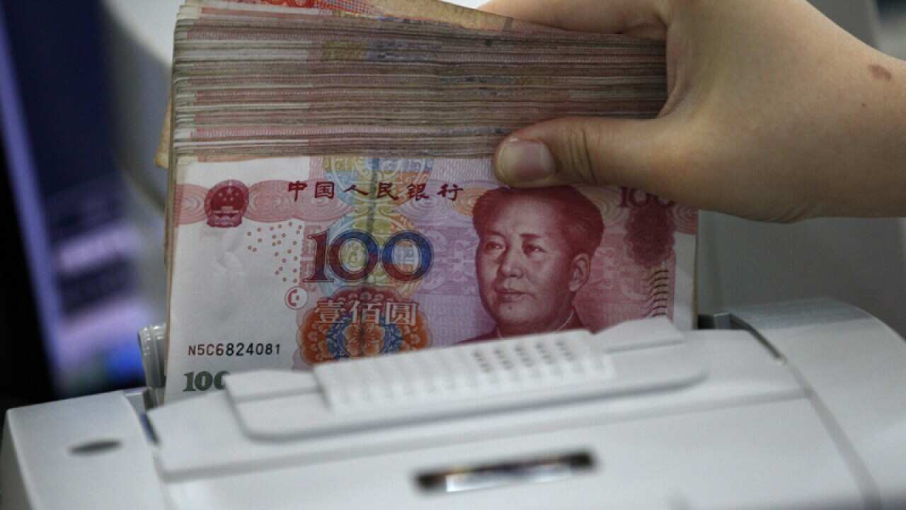 A clerk counting Renminbi banknotes in a bank outlet in Huaibei