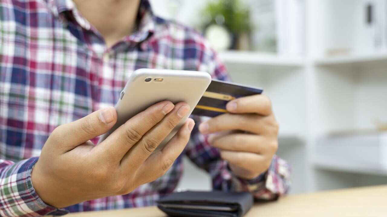 Young man hands holding credit card and using phone