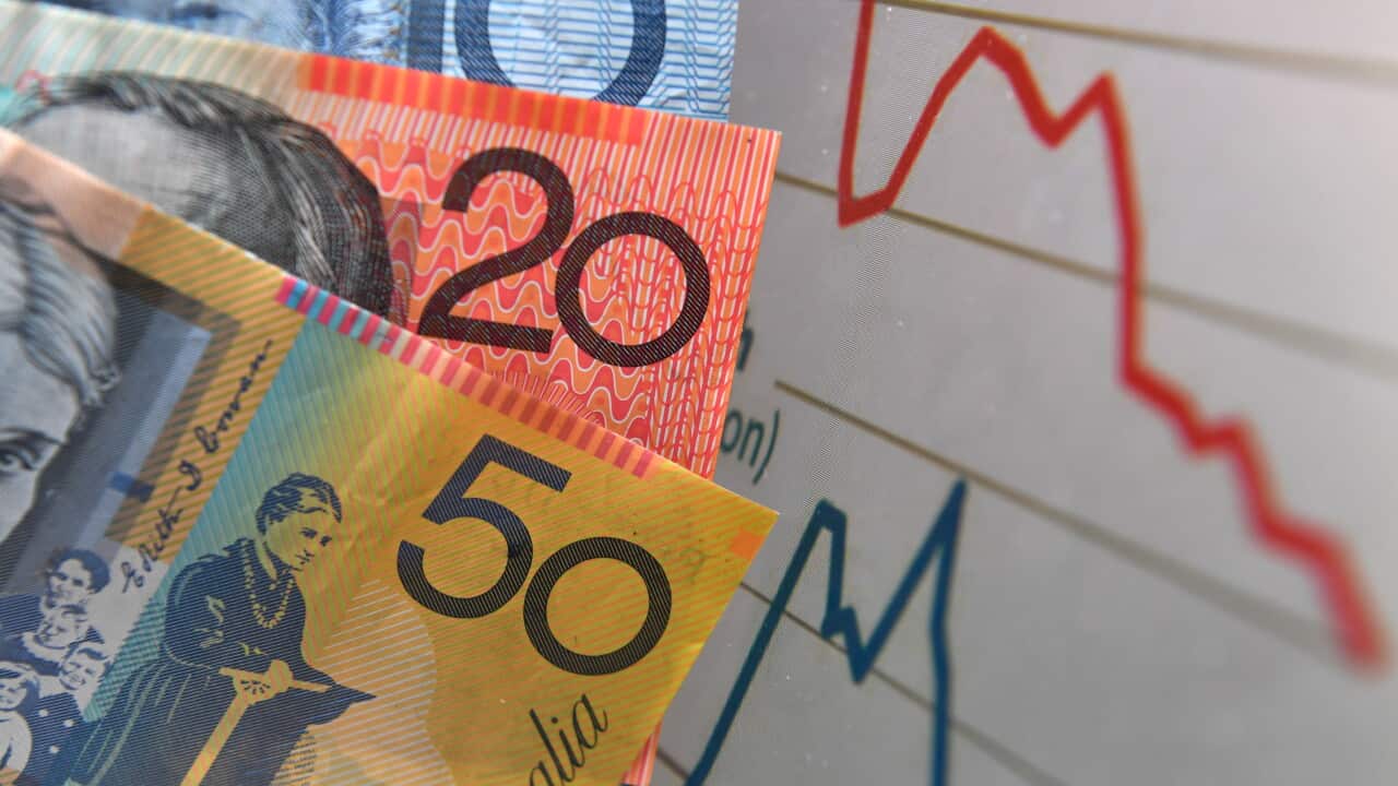 Cash notes held up in front of a line graph.