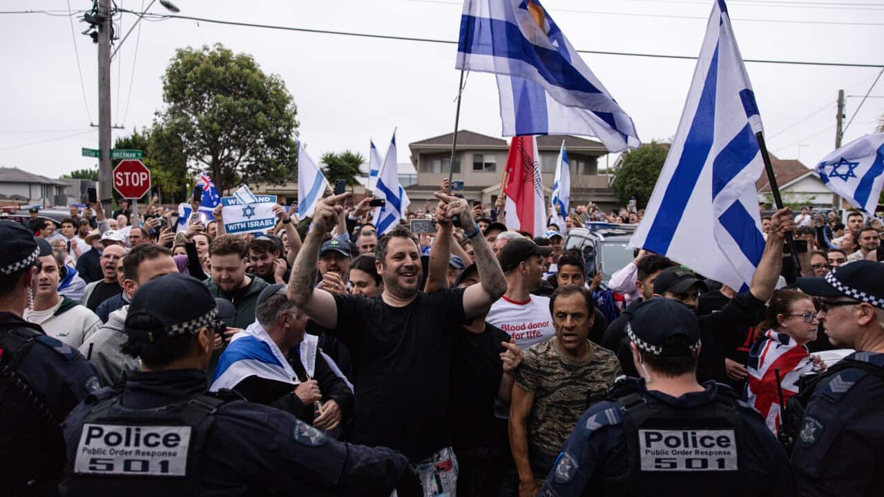 Protesters, some holding Israeli flags, are being monitored by police.
