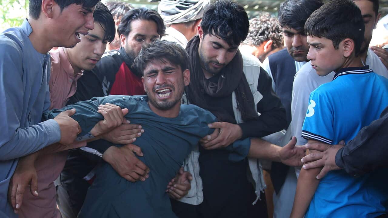 Relatives grieve near the coffins of victims of the Dubai City wedding hall bombing during a mass funeral in Kabul, Afghanistan.